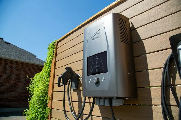 Borne de recharge pour véhicule électrique fixée sur une façade