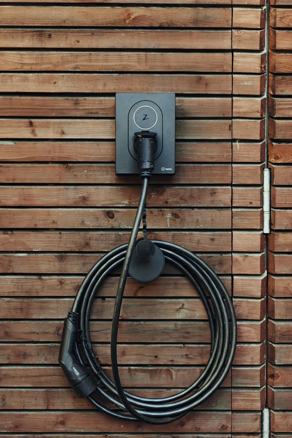 Câble de recharge enroulé le long d’un mur en bois