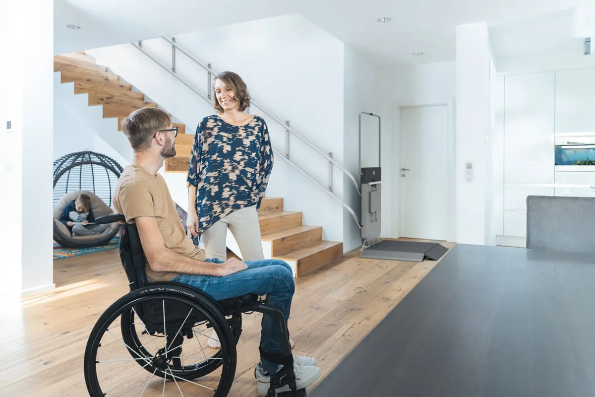 Deux personnes, dont une en fauteuil roulant, près d’une plateforme élévatrice