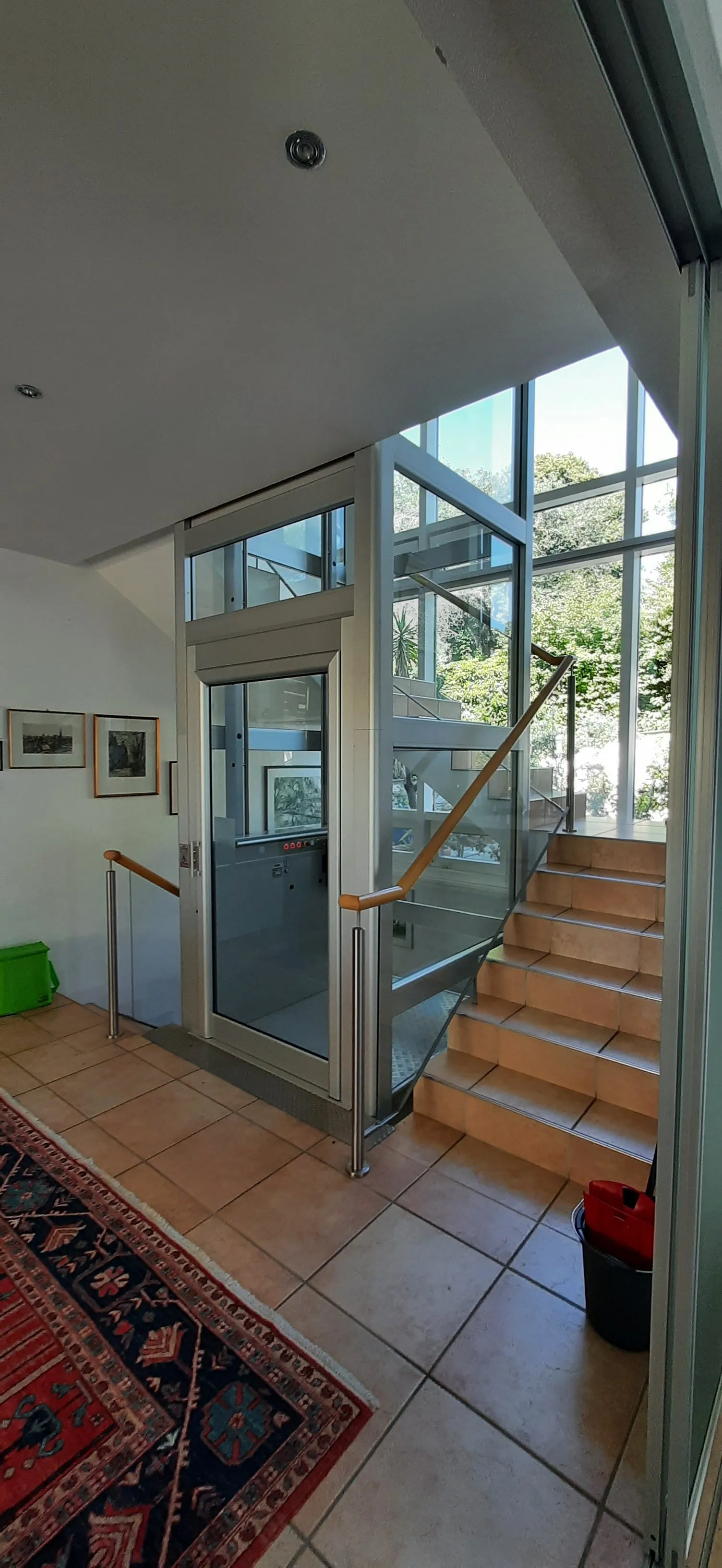 Élévateur vitré longeant un escalier en bois