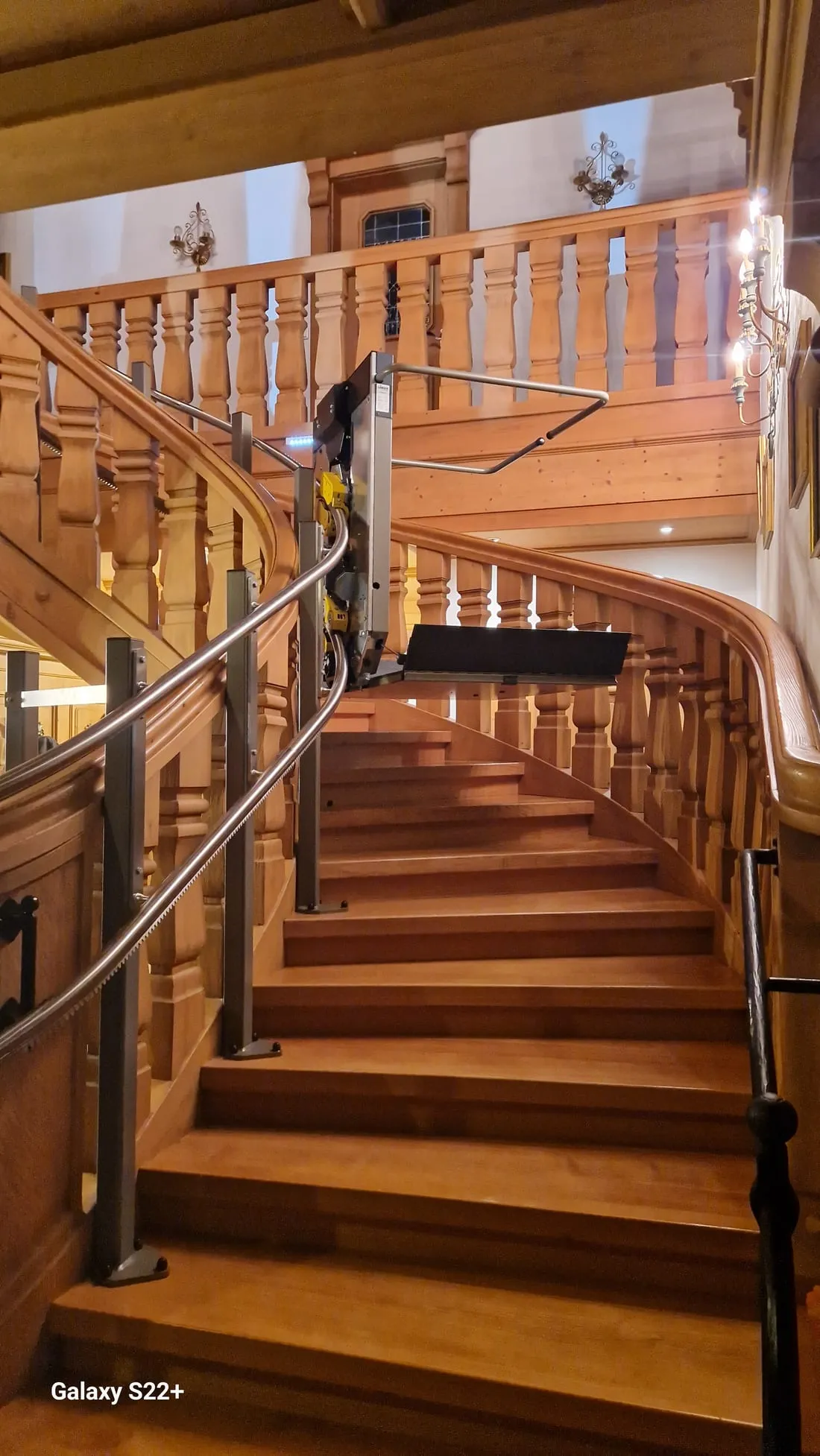 Plateforme élévatrice inclinée longeant un escalier tournant en bois