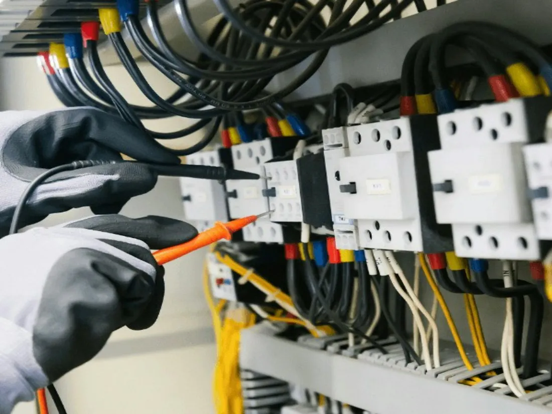 Technicien contrôlant une armoire électrique au multimètre