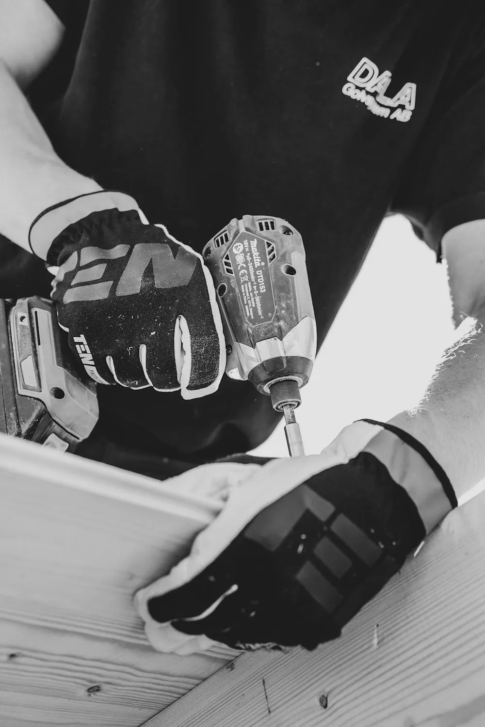 Mains gantées vissant une fixation à l’aide d’une visseuse